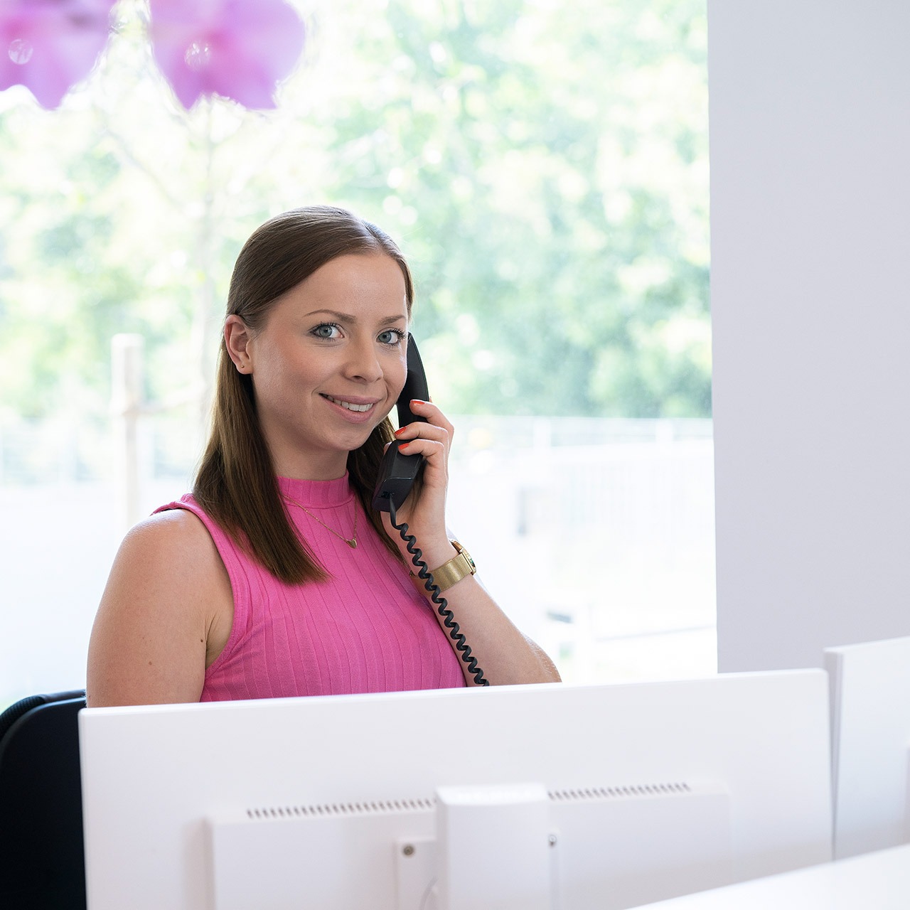 Annette Scherer telefoniert am Empfang – Personalaufnahme Personalaufnahme von junger Frau in einem Büro, sie telefoniert an ihrem Arbeitsplatz