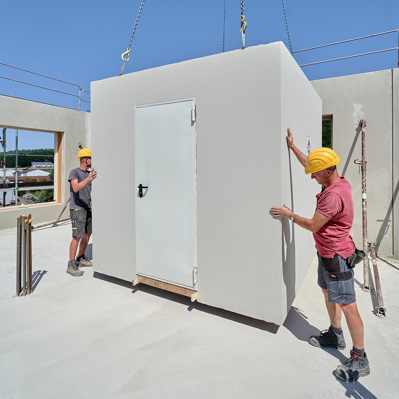 Badzelle montieren auf Baustelle Baustellenaufnahme, zwei Männer stellen Badzelle