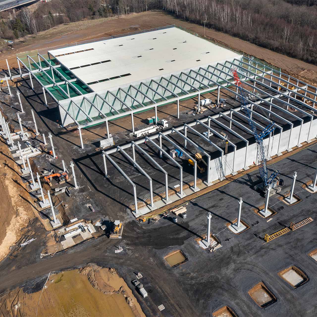 Luftaufnahme von Gewerbehalle im Bauzustand. Stützen und Binder werden gerade gestellt.